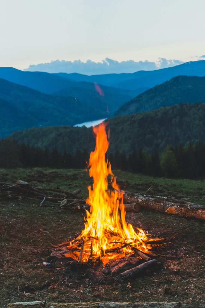 A serene campfire with a stunning mountain backdrop in Romania's Lunca Vişagului.